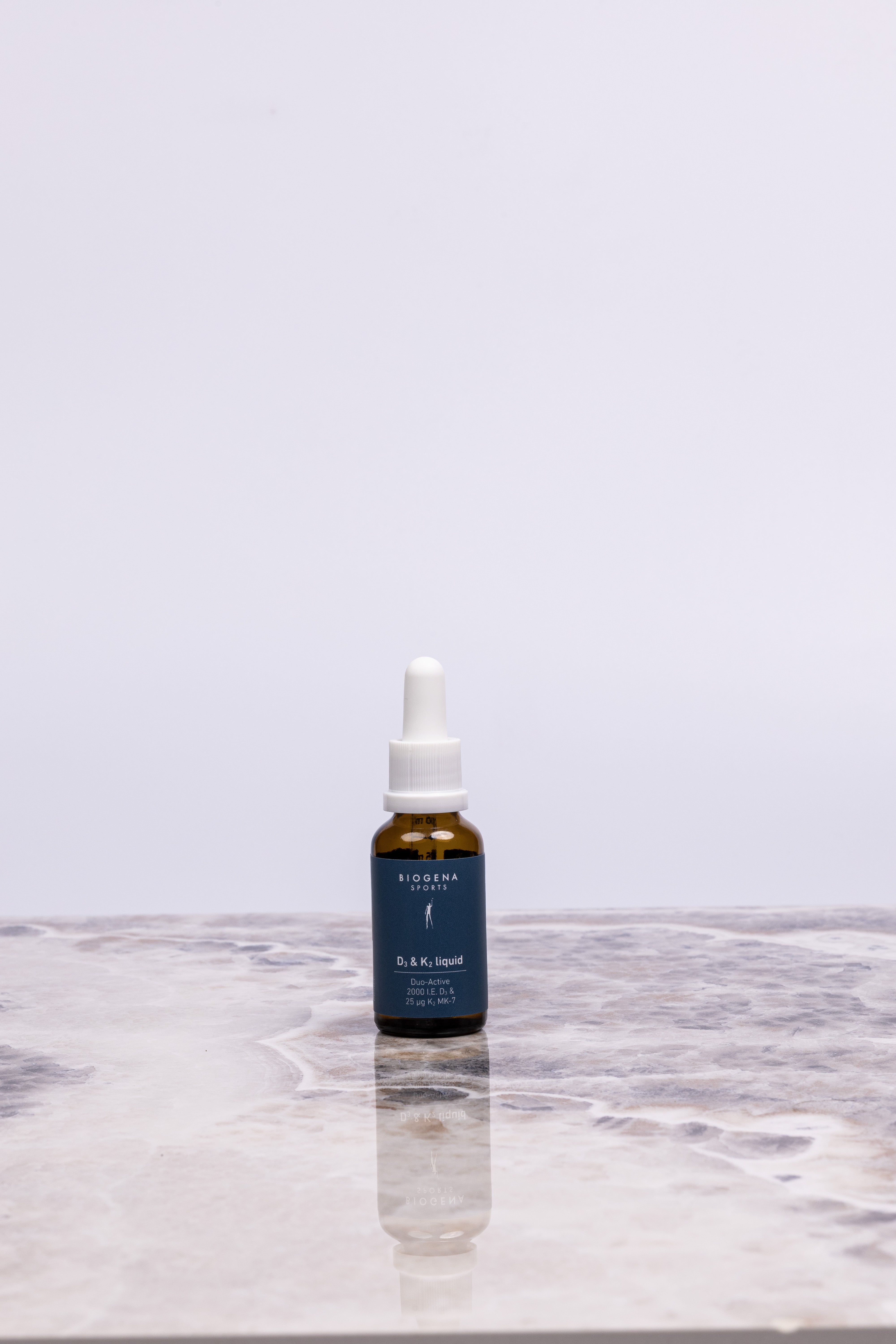 BIOGENA SPORTS D3 & K2 liquid Flasche steht auf einer Marmorplatte.