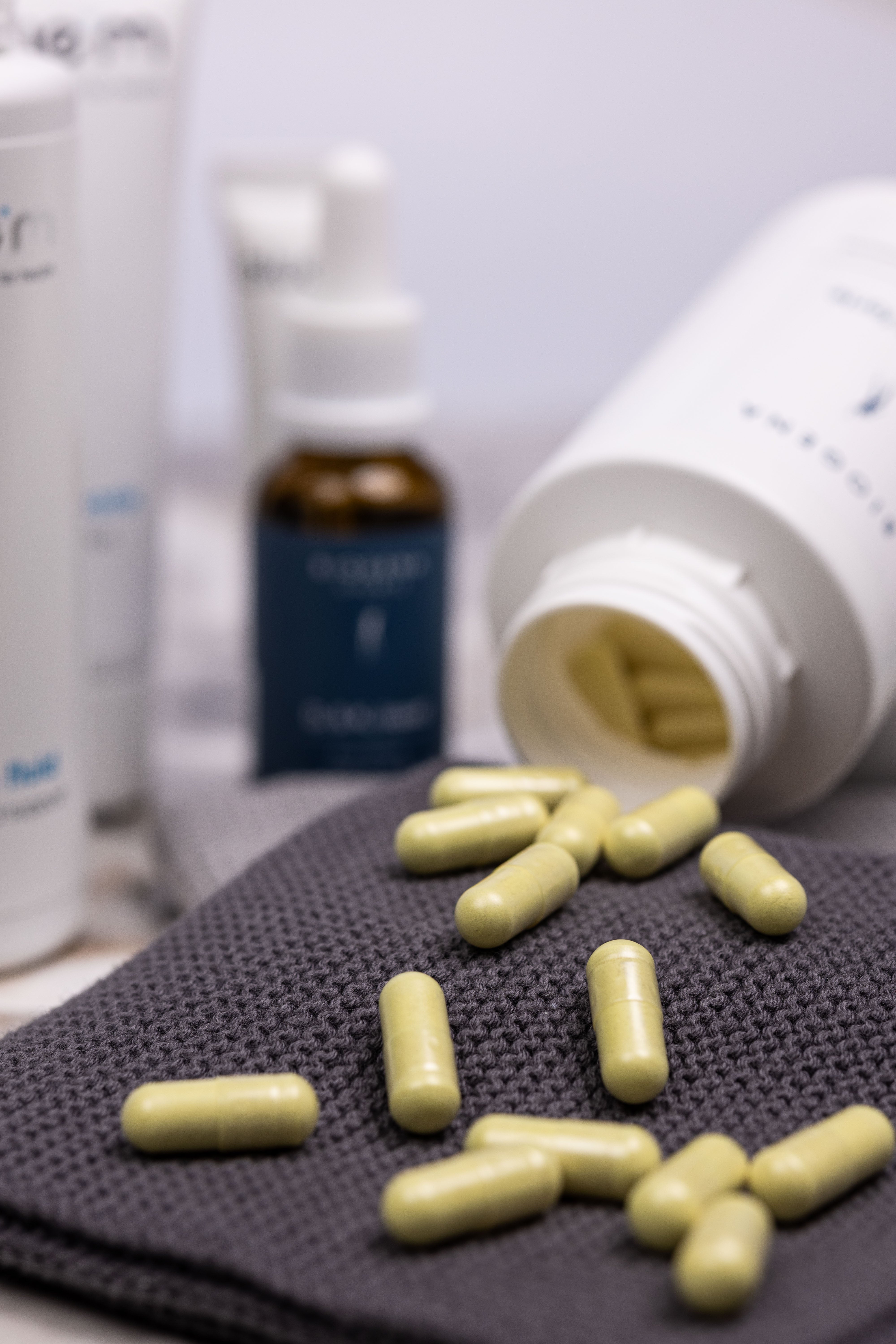 Verpackungsdose von Biogena DoloZym forte liegt geöffnet auf einem grauen Handtuch, die enthaltenen gelben Kapseln liegen vor der Verpackung.