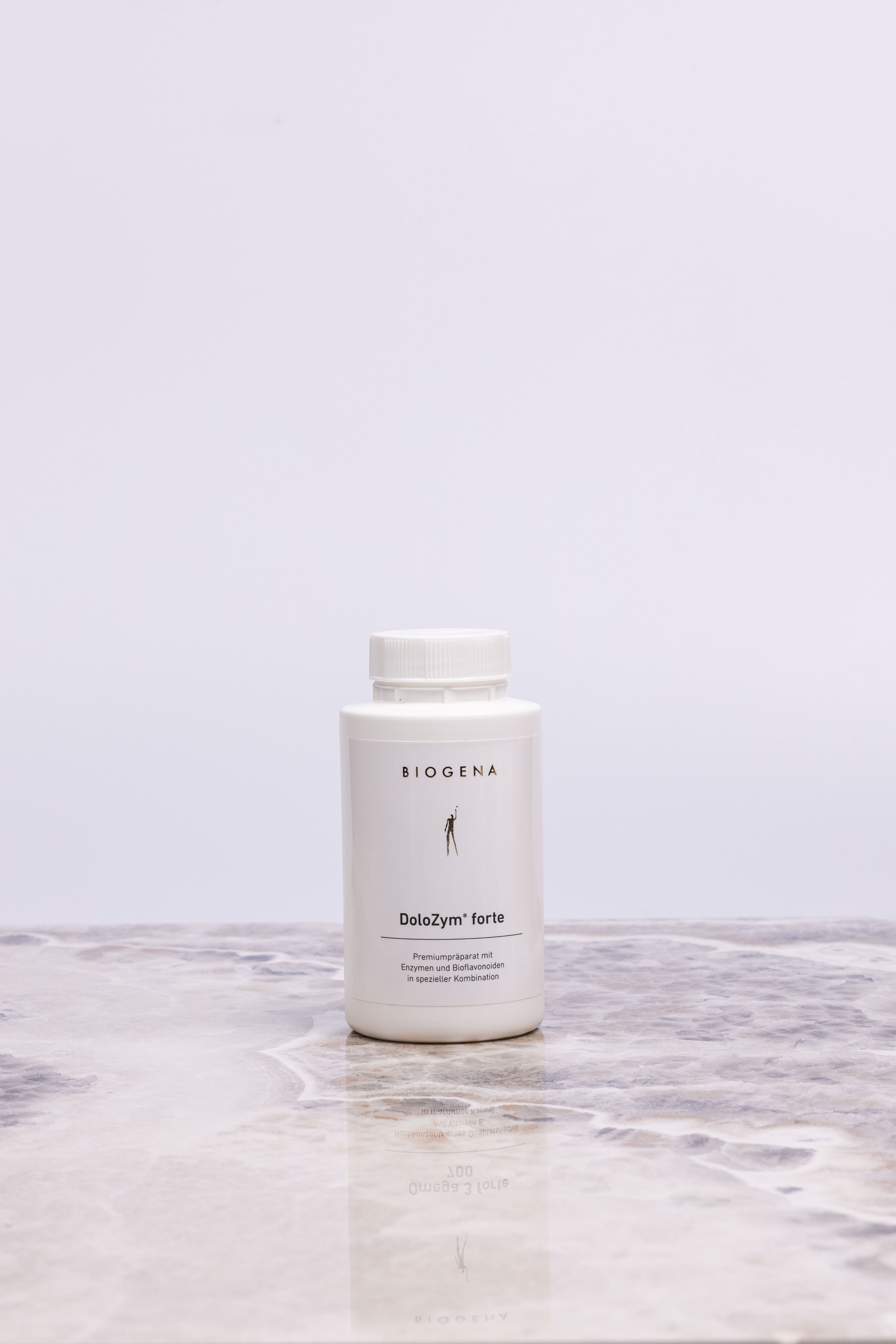 Geschlossene Verpackungsdose Biogena DoloZym forte steht auf einer Marmorplatte.