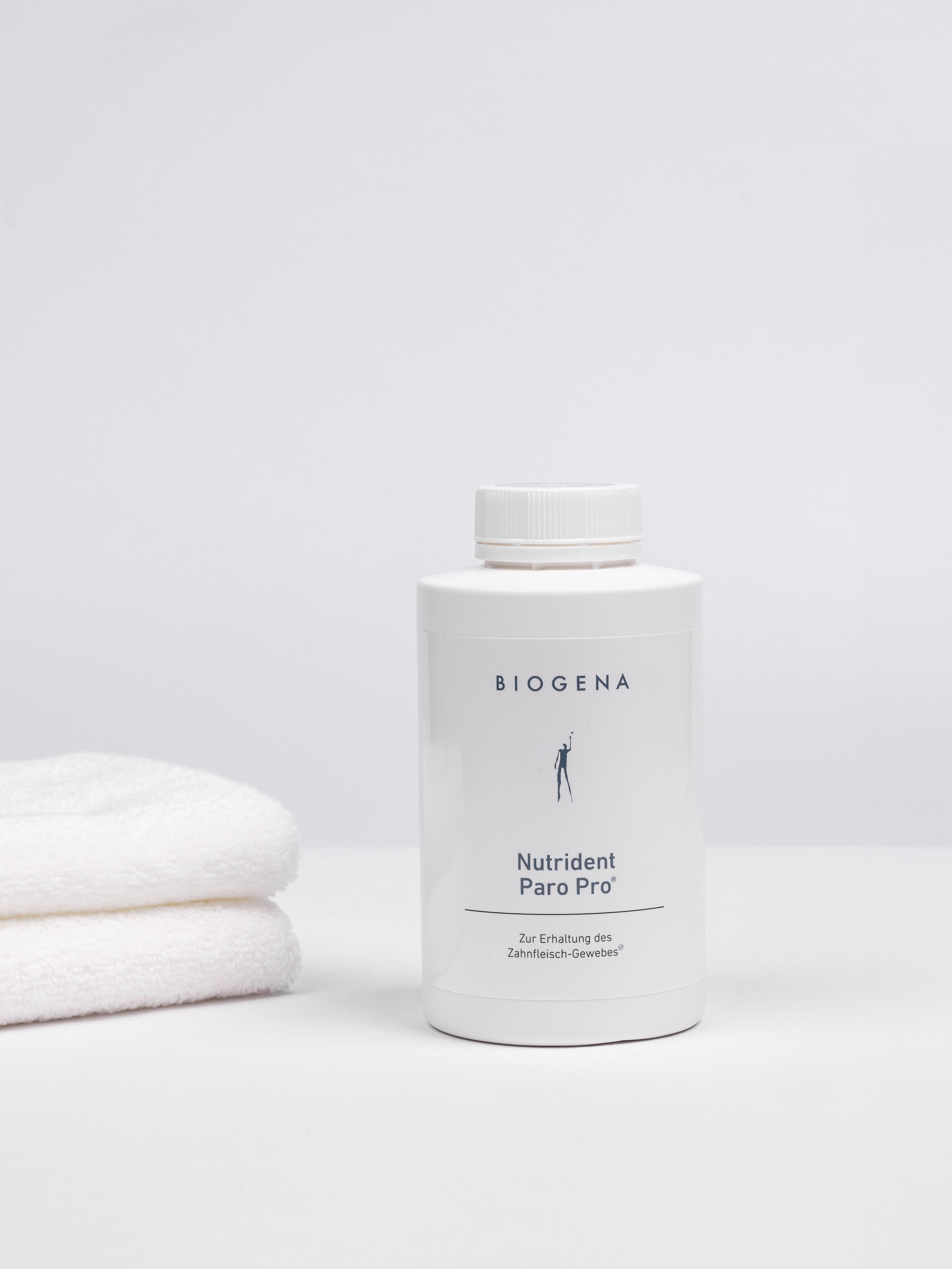 Geschlossene Verpackungsdose Nutrident Paro Pro, links daneben ein Stapel weißer Handtücher.
