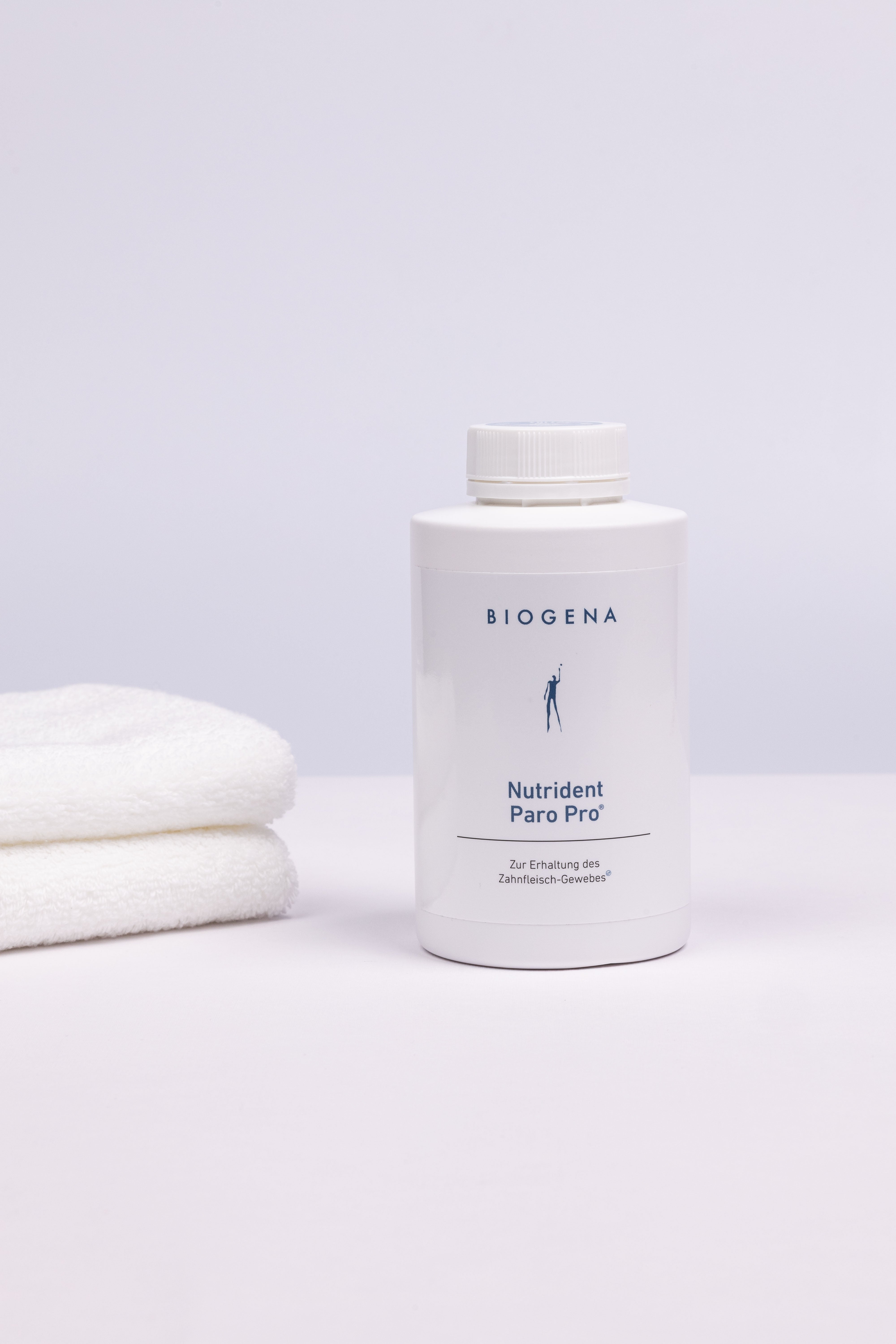 Geschlossene Verpackungsdose Nutrident Paro Pro, links daneben ein Stapel weißer Handtücher.
