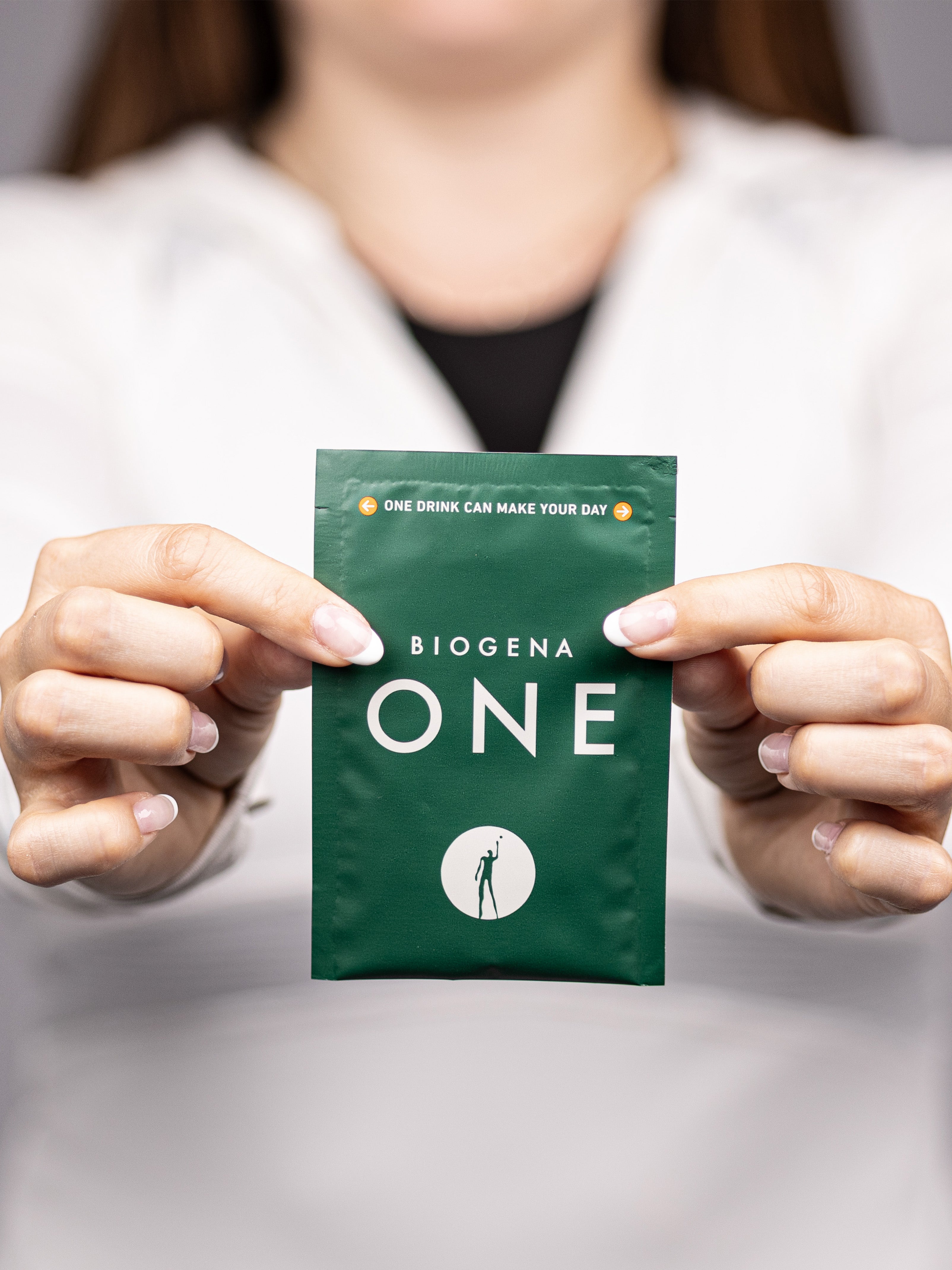 Frau hält den BIOGENA ONE All-in-One Supplement-Drink Portionsbeutel in beiden Händen.