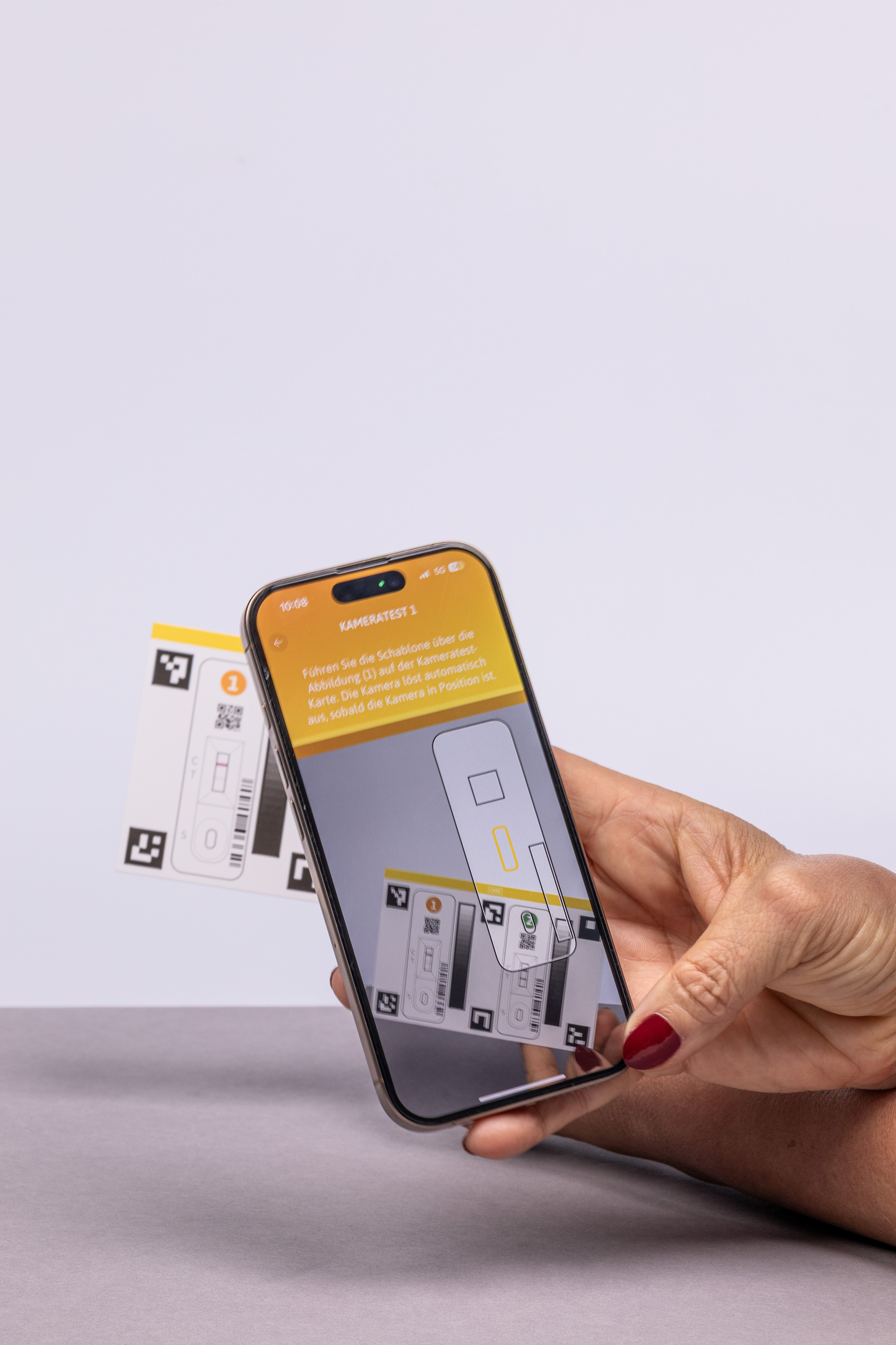 Frau hält ein Smartphone in der Hand auf dem Display erscheint der Scan des Teststreifens.