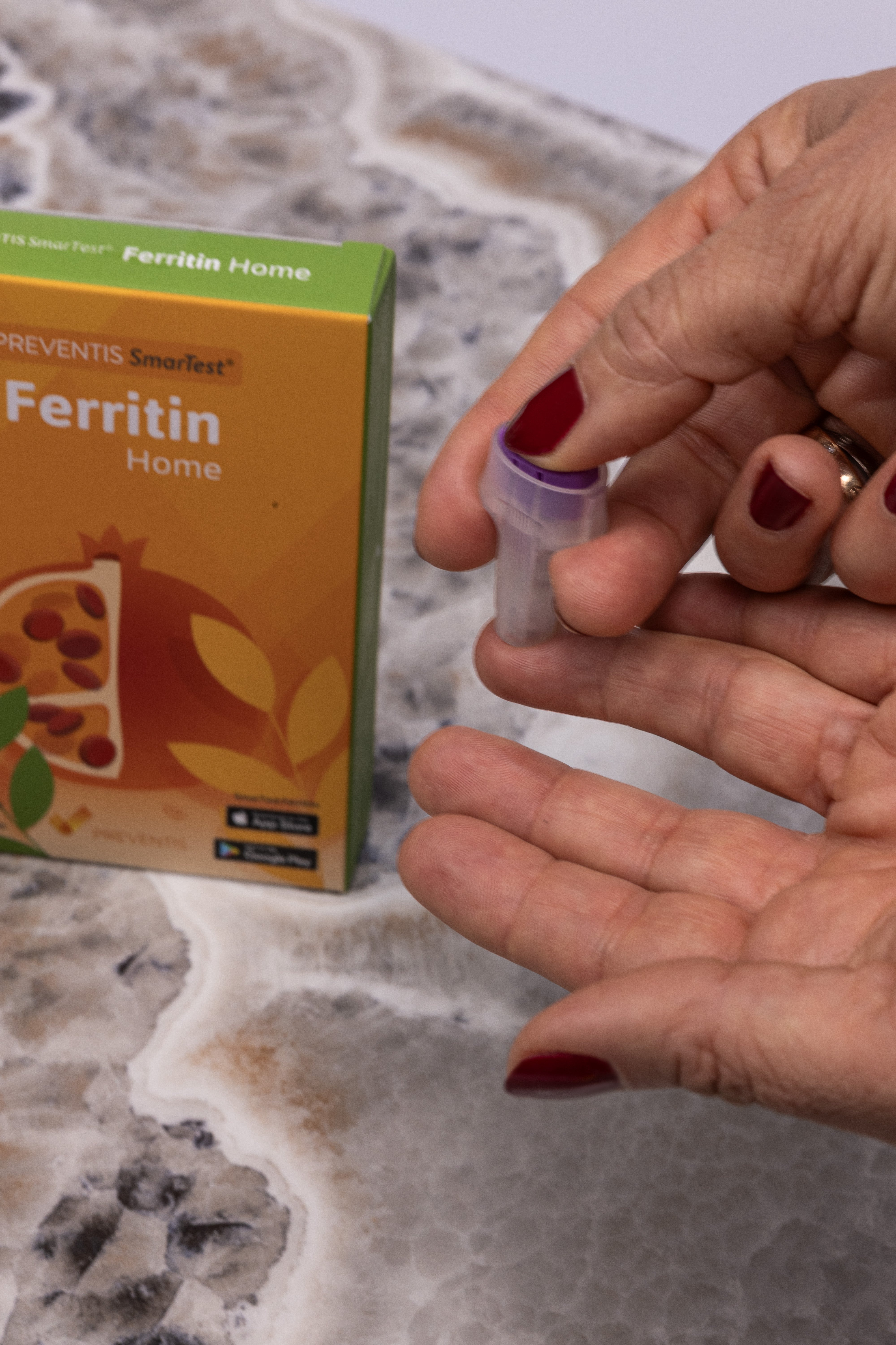 Darstellung des Testvorgang des Ferritin Schnelltests, dabei sind zwei Frauenhände zu sehen. Eine Hand nutzt die spezielle Stechhilfe, um in die Fingerkuppe des Mittelfingers der anderen Hand zu stechen.