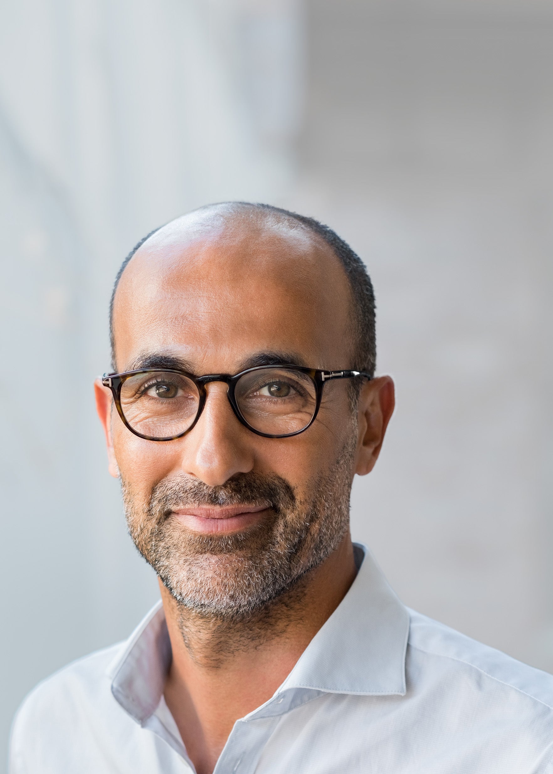 Zahnarzt mittleren Alters mit kurzen Haaren, Brille und einem kurzen Bart schaut freundlich in die Kamera.
