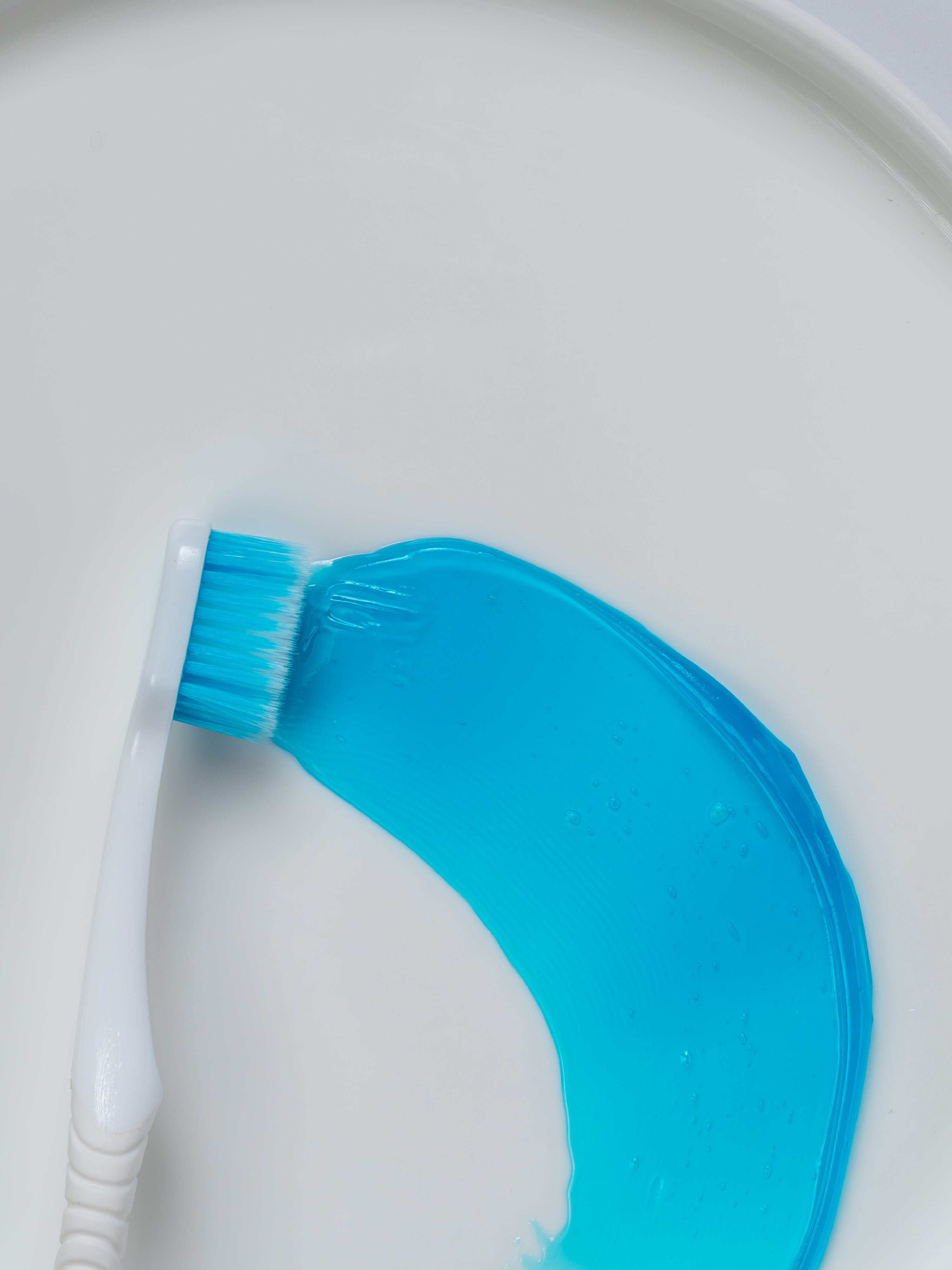 Zahnbürste mit der hellblaues Zahngel verstrichen wurde.