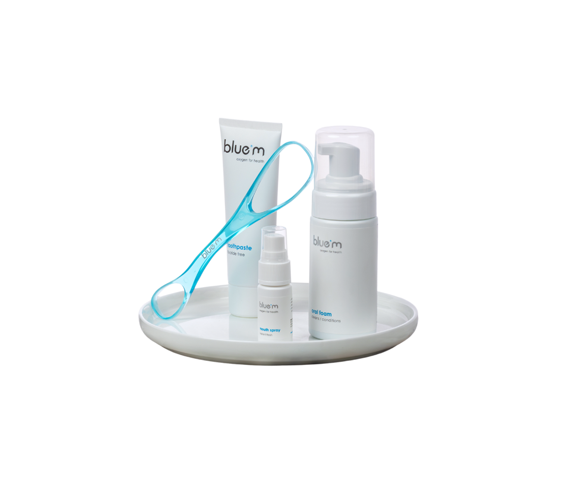 Pflegeset bei Diabetes bestehend aus einem Zungenreiniger, Zahngel, Mundspray und Mundschaum arrangiert auf einem weißen Tablett.