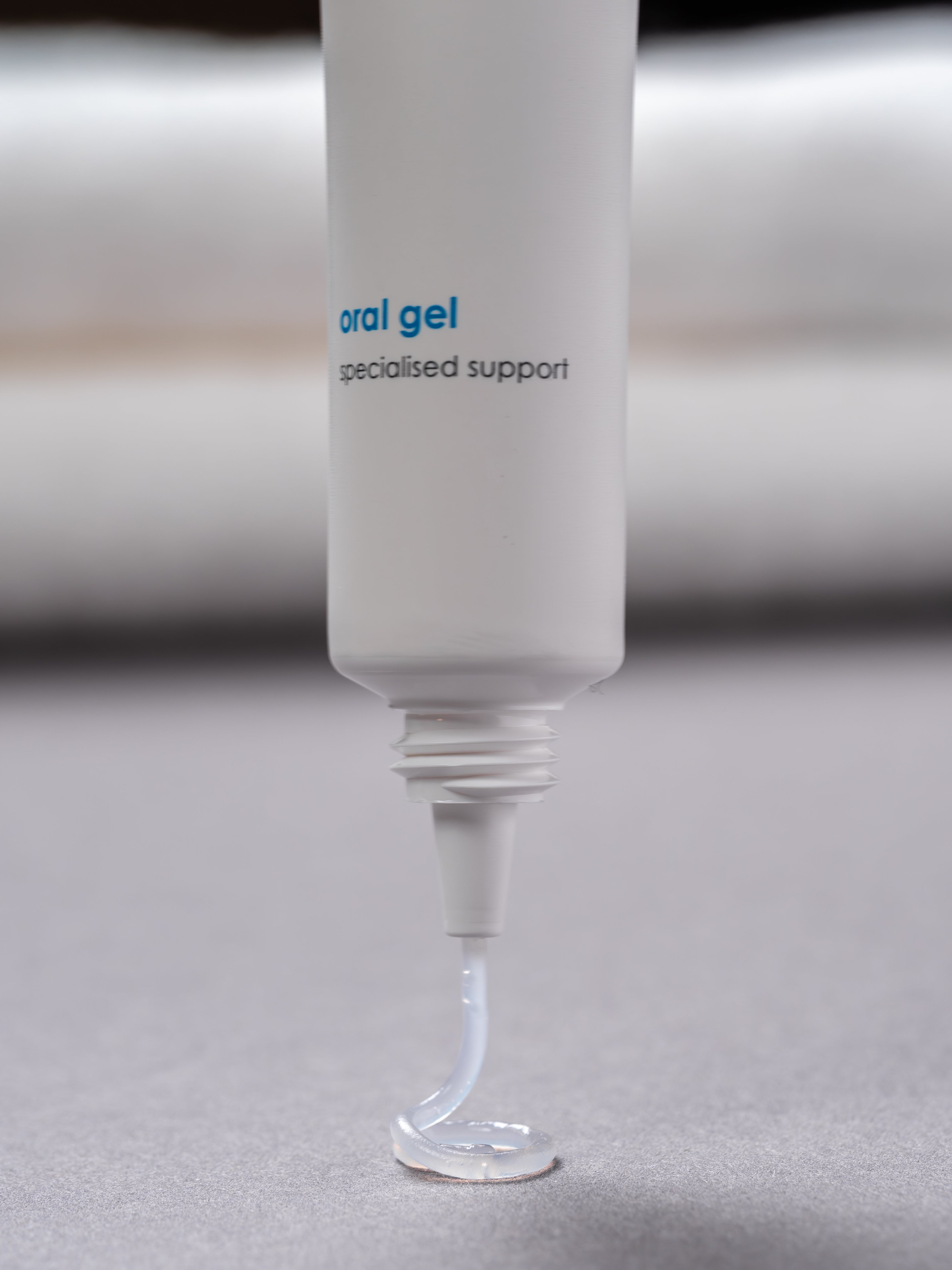 Eine senkrecht stehende Tube Mundgel aus der das Gel kreisförmig herausfließt.