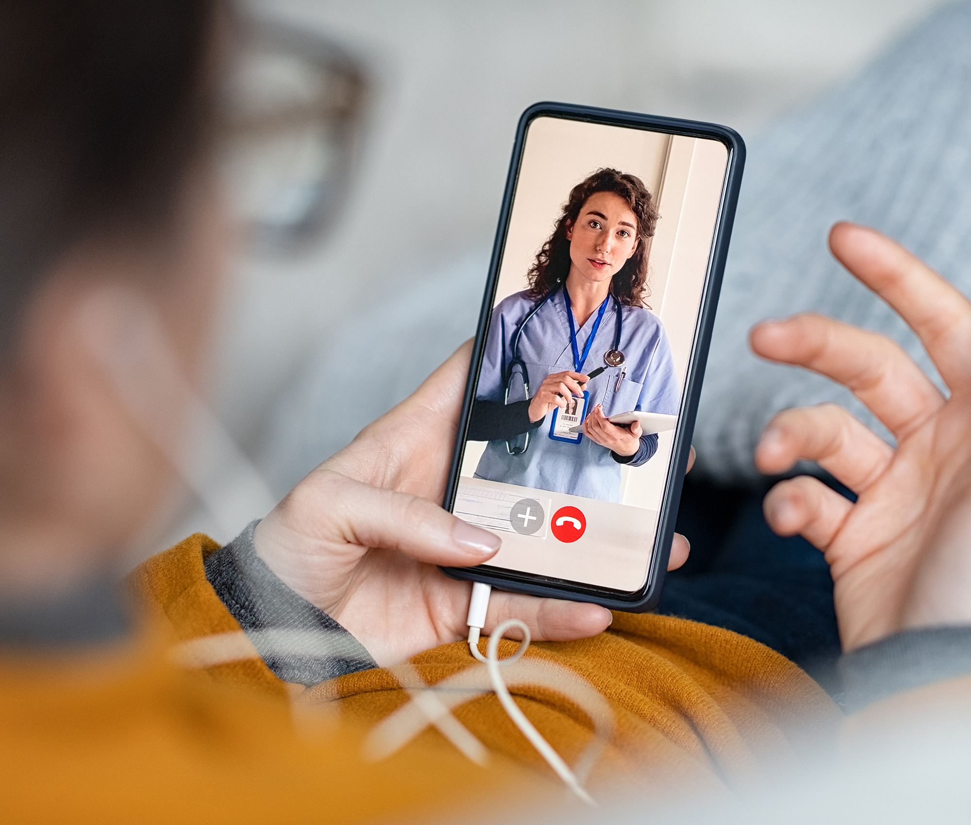 Eine Frau hält ein Smartphone in den Händen. Auf dem Bildschirm ist eine junge Zahnärztin erkennbar mit der sie einen Video-Call hat.