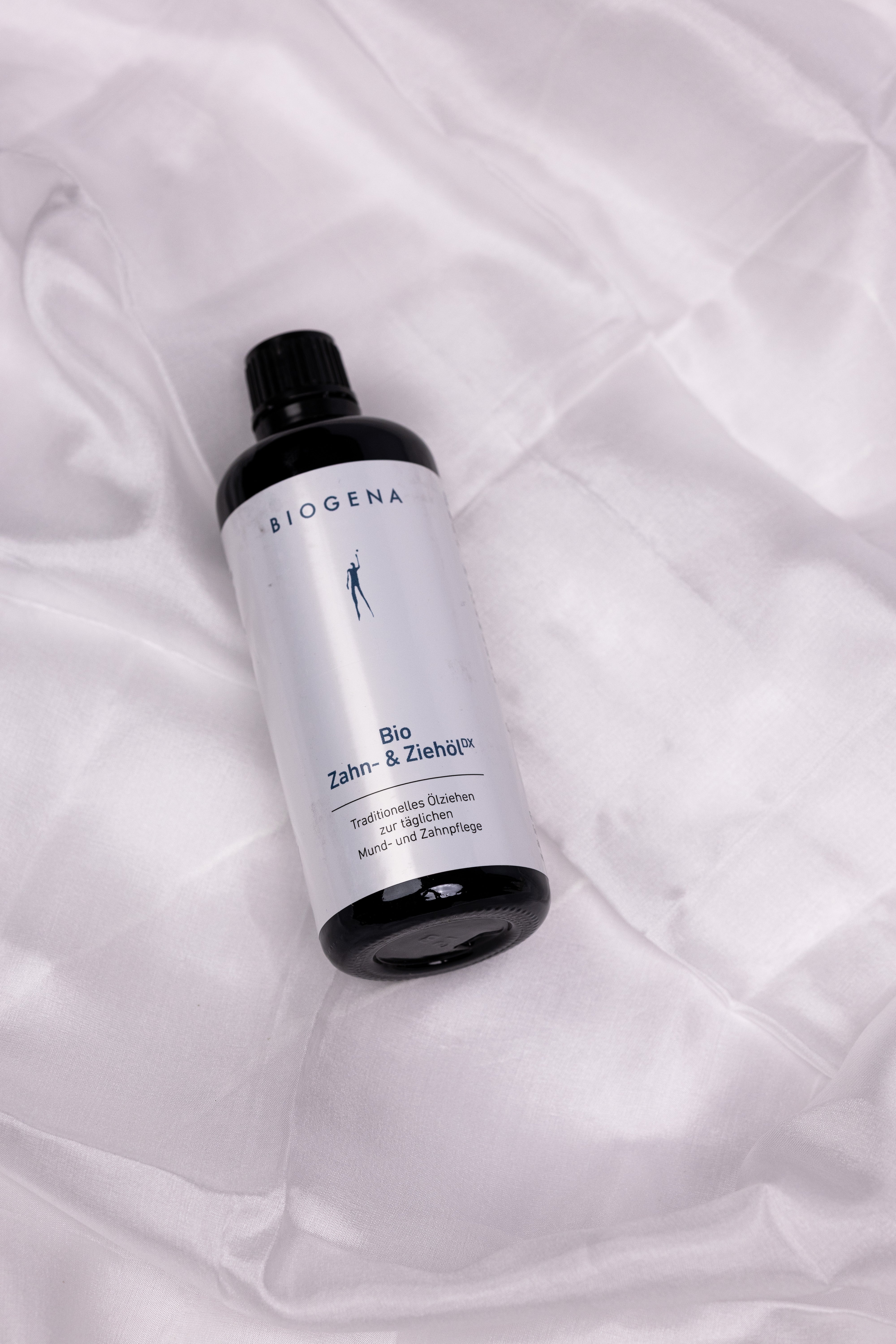 BIOGENA Zahn- und Ziehöl Flasche auf einem weißen Stofftuch liegend.