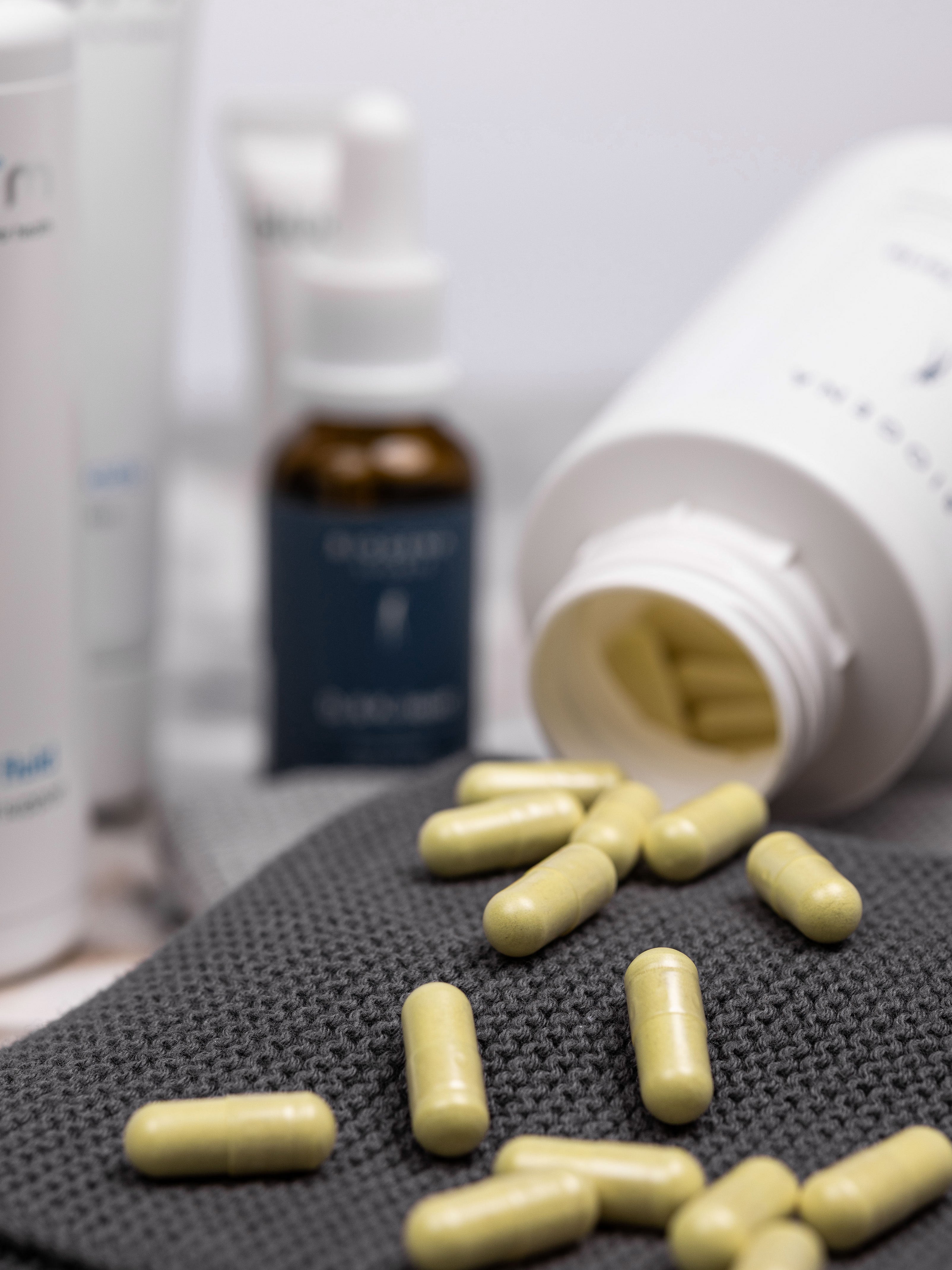 Verpackungsdose von Biogena DoloZym forte liegt geöffnet auf einem grauen Handtuch, die enthaltenen gelben Kapseln liegen vor der Verpackung.