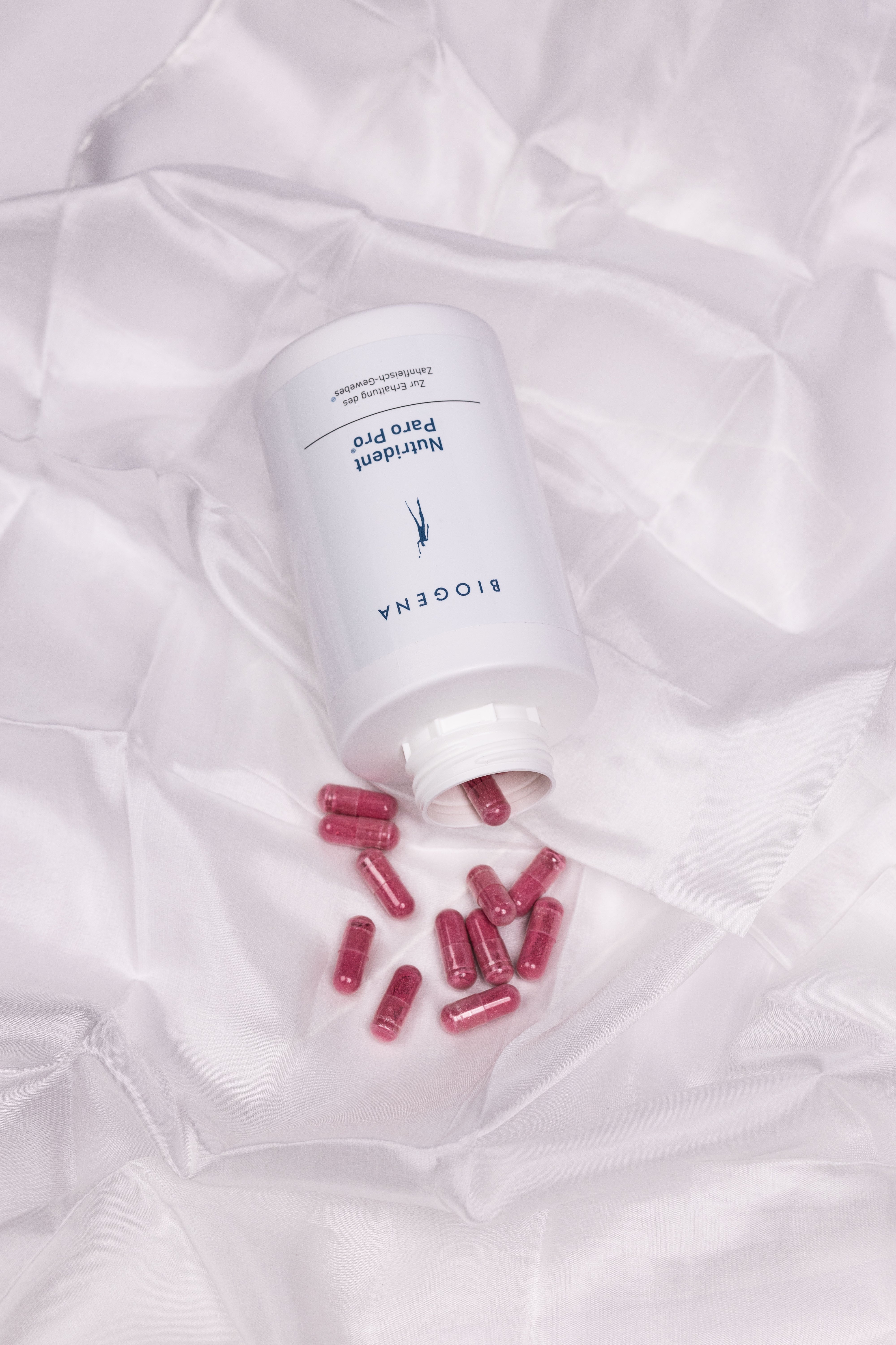Verpackungsdose von Nutrident Paro Pro liegend auf einem weißen Tuch, die enthaltenen roten Kapseln liegen vor der Verpackung.