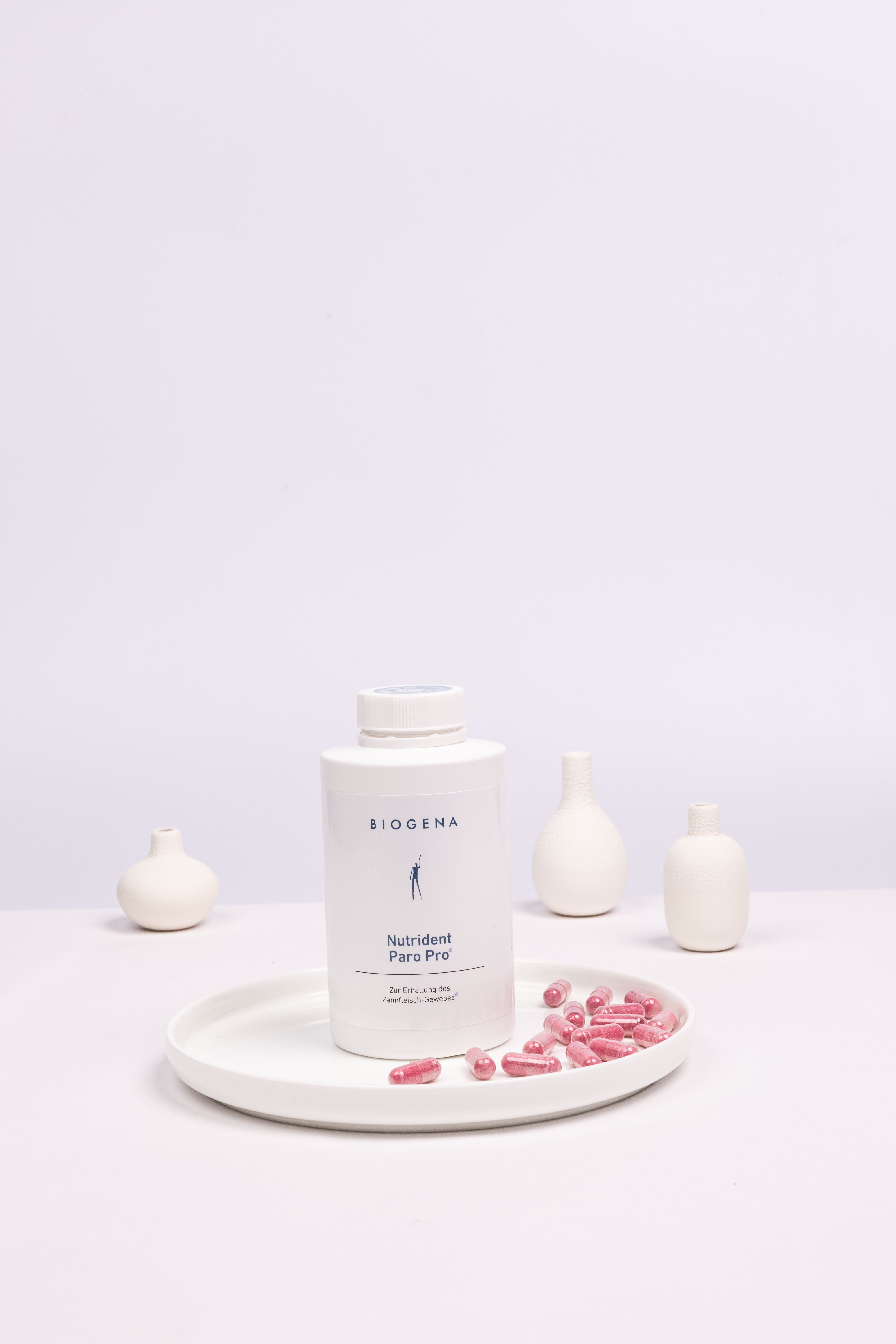 Geschlossene Verpackung von Nutrident Paro Pro steht auf einem weißen Tablett umgeben von roten Kapseln.