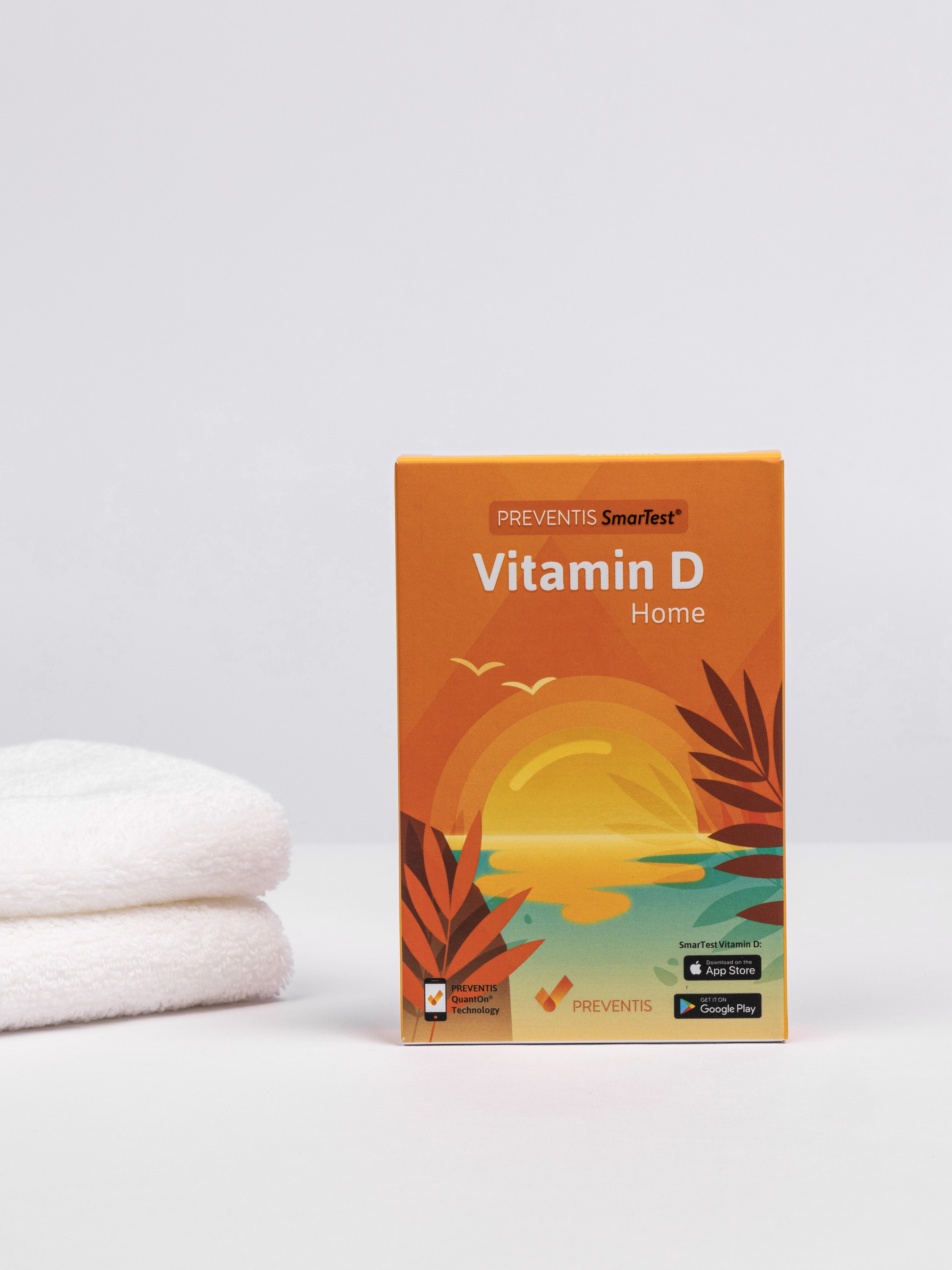 Vitamin D Schnelltest Verpackung links daneben ein Stapel weiße Handtücher.