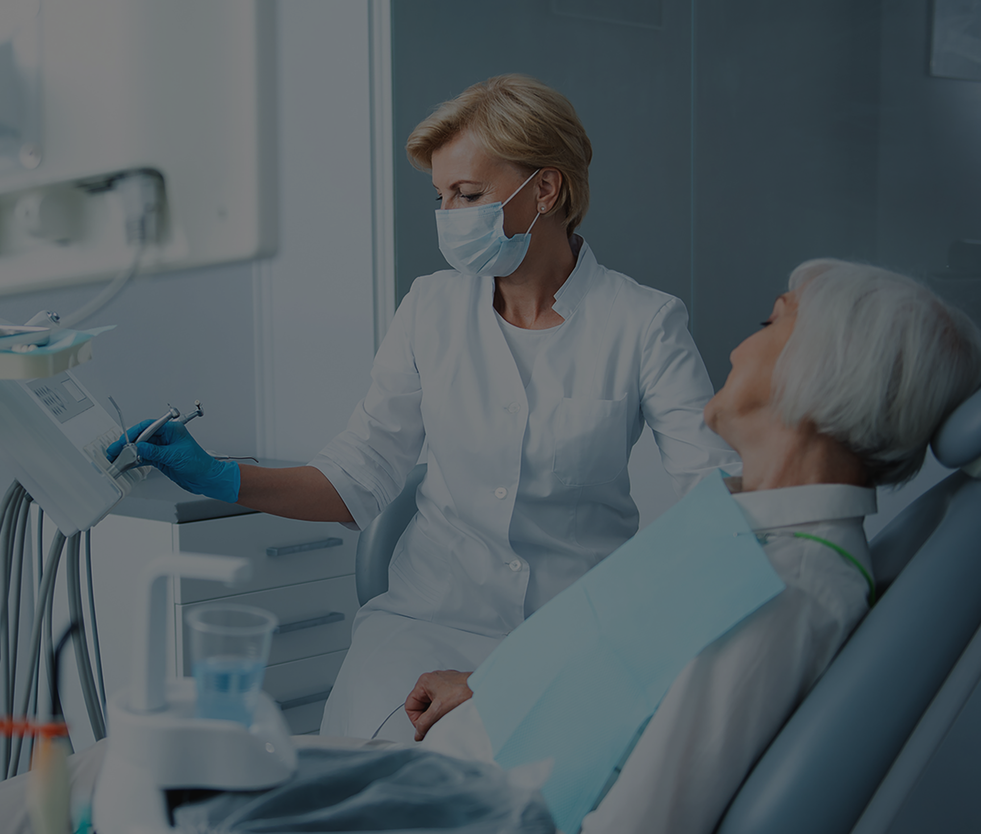 Zahnärztin und ältere Patientin sind gemeinsam im Behandlungszimmer einer Zahnarztpraxis. Die Zahnärztin greift nach den Behandlungsinstrumenten, die Patienten ist der Zahnärztin zugewandt.
